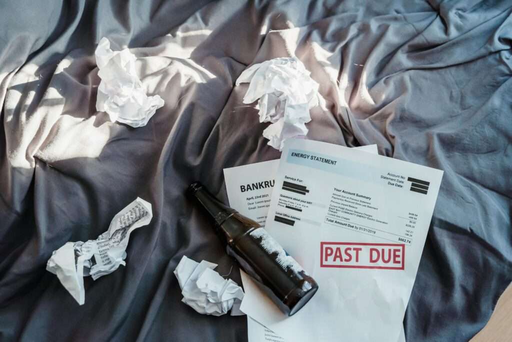 Scene of financial distress with bankruptcy notice, past due bills, and crumpled papers on a bed.