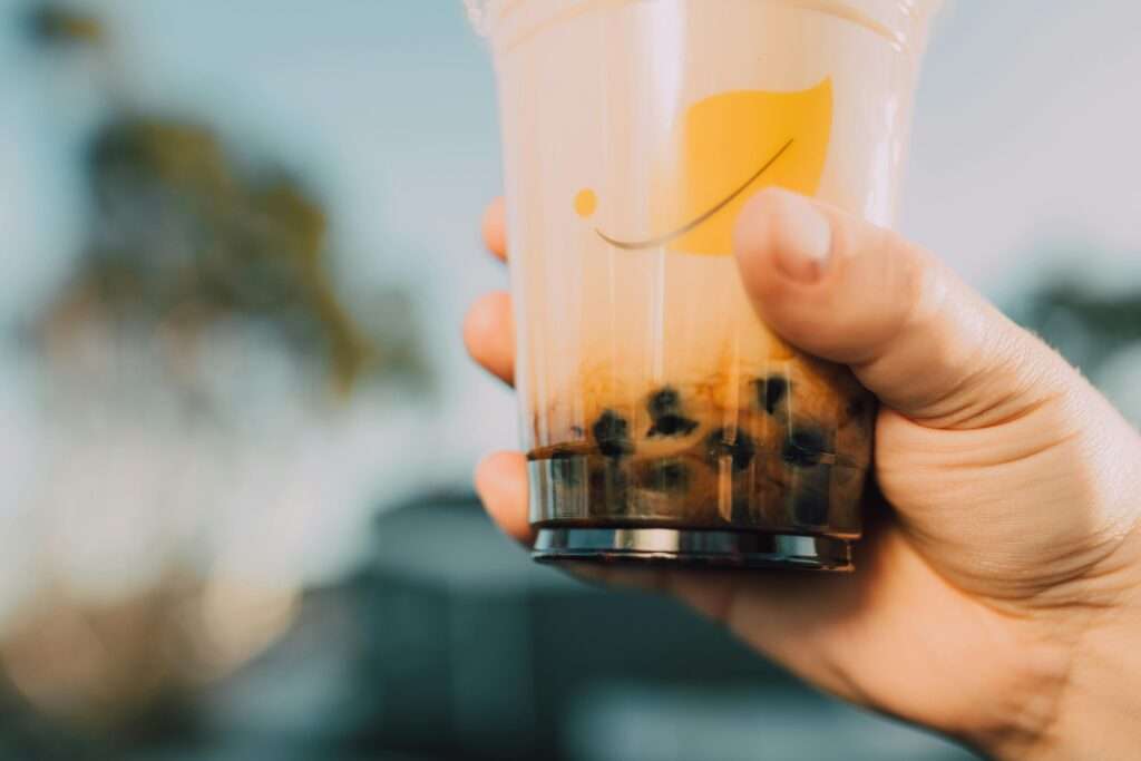 Vibrant image of a hand holding a bubble tea cup with a blurred background. Refreshing and trendy.